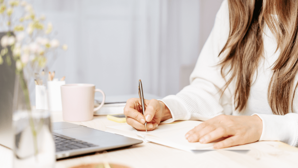 Woman writing down ideas from a book in her journal