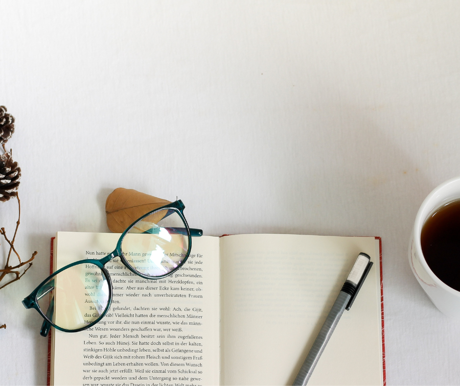 Open book with a pen and glasses on the desk