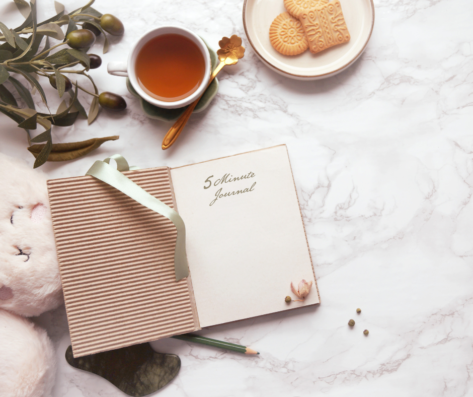 Photo of the journal on the table, tea and cookies. 5 Minute Journal helps you reflect on the mindset shifts you need to advance your life.