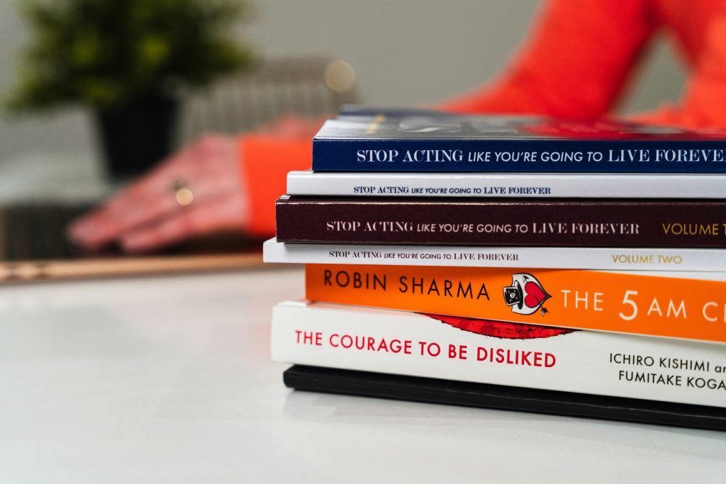 Books on the desk, one of the books is Robin Sharma The 5am Club